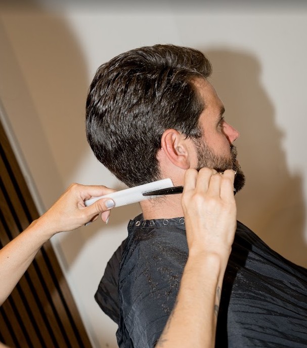 Barber demonstrating how to do scissor over comb technique on a client's hair